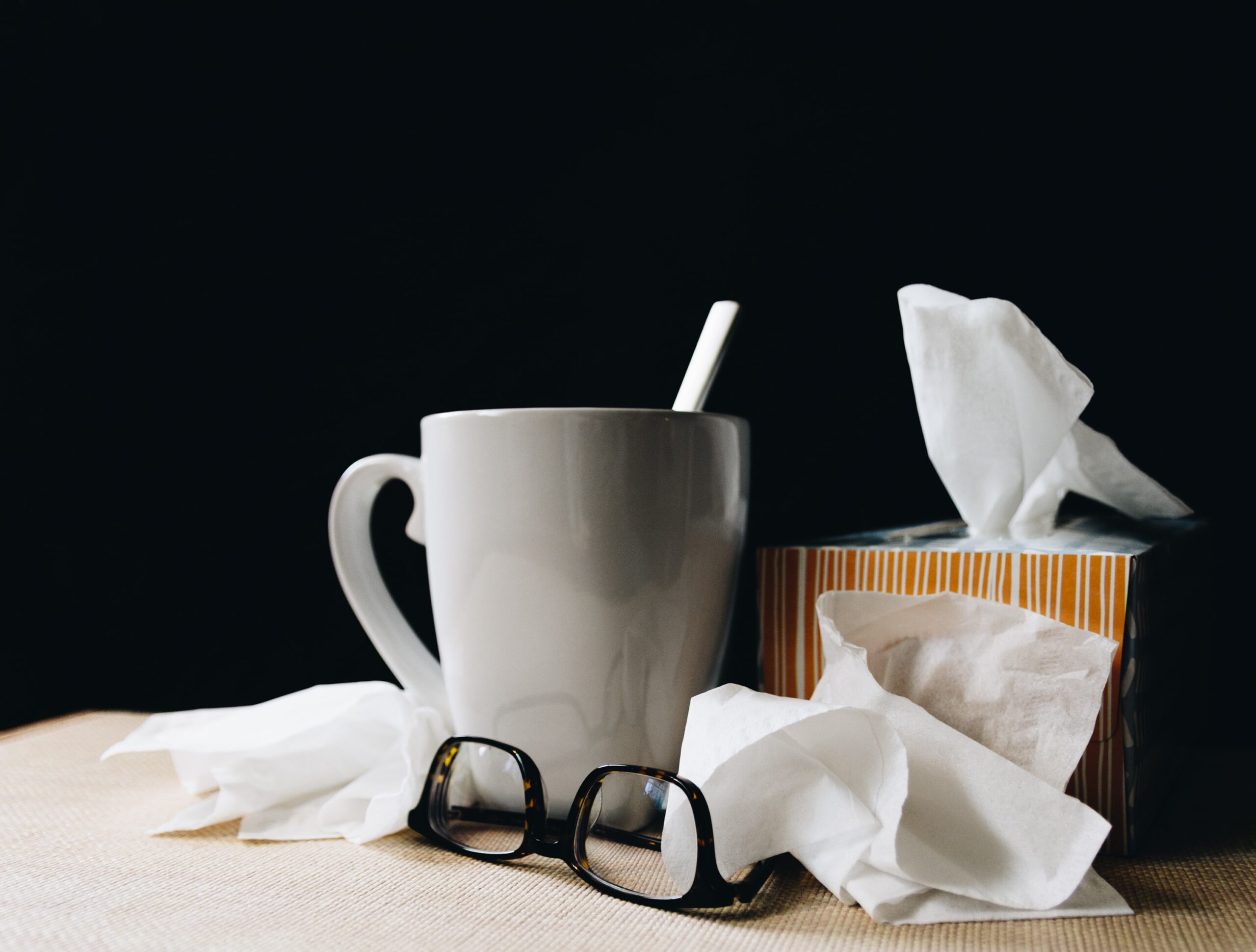 Photo of a mug, glasses and used tissue on a table