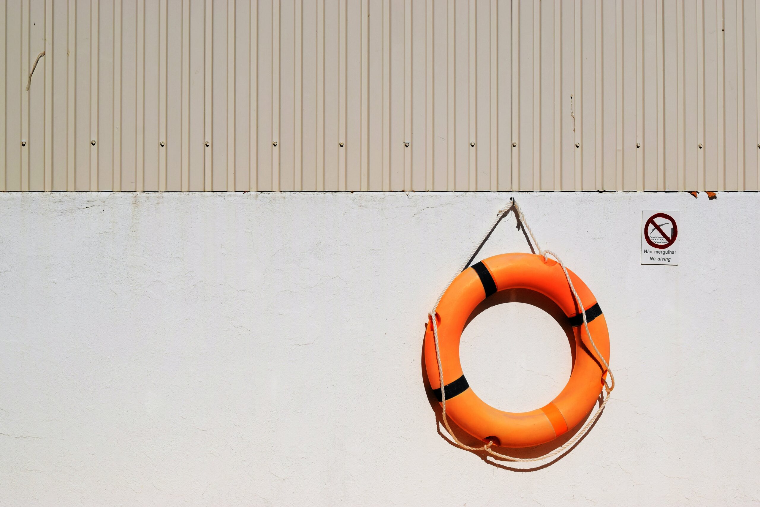 Orange life ring hanging on a beige wall