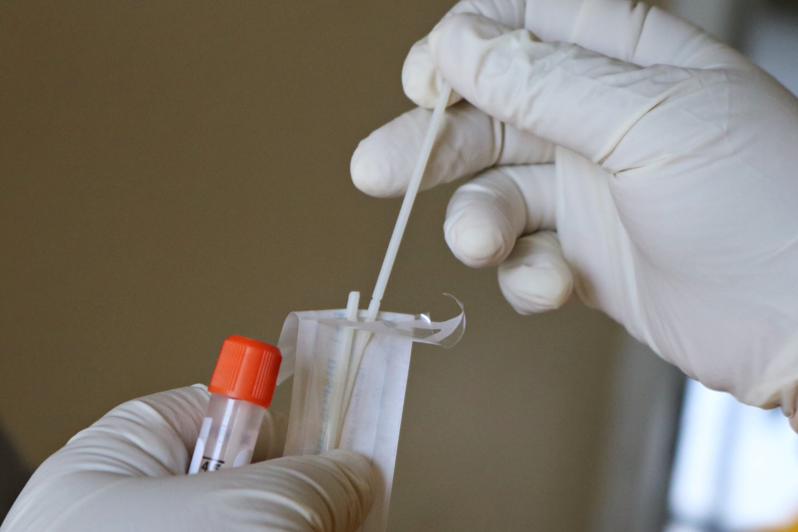 Gloved hands taking a swab out of packaging