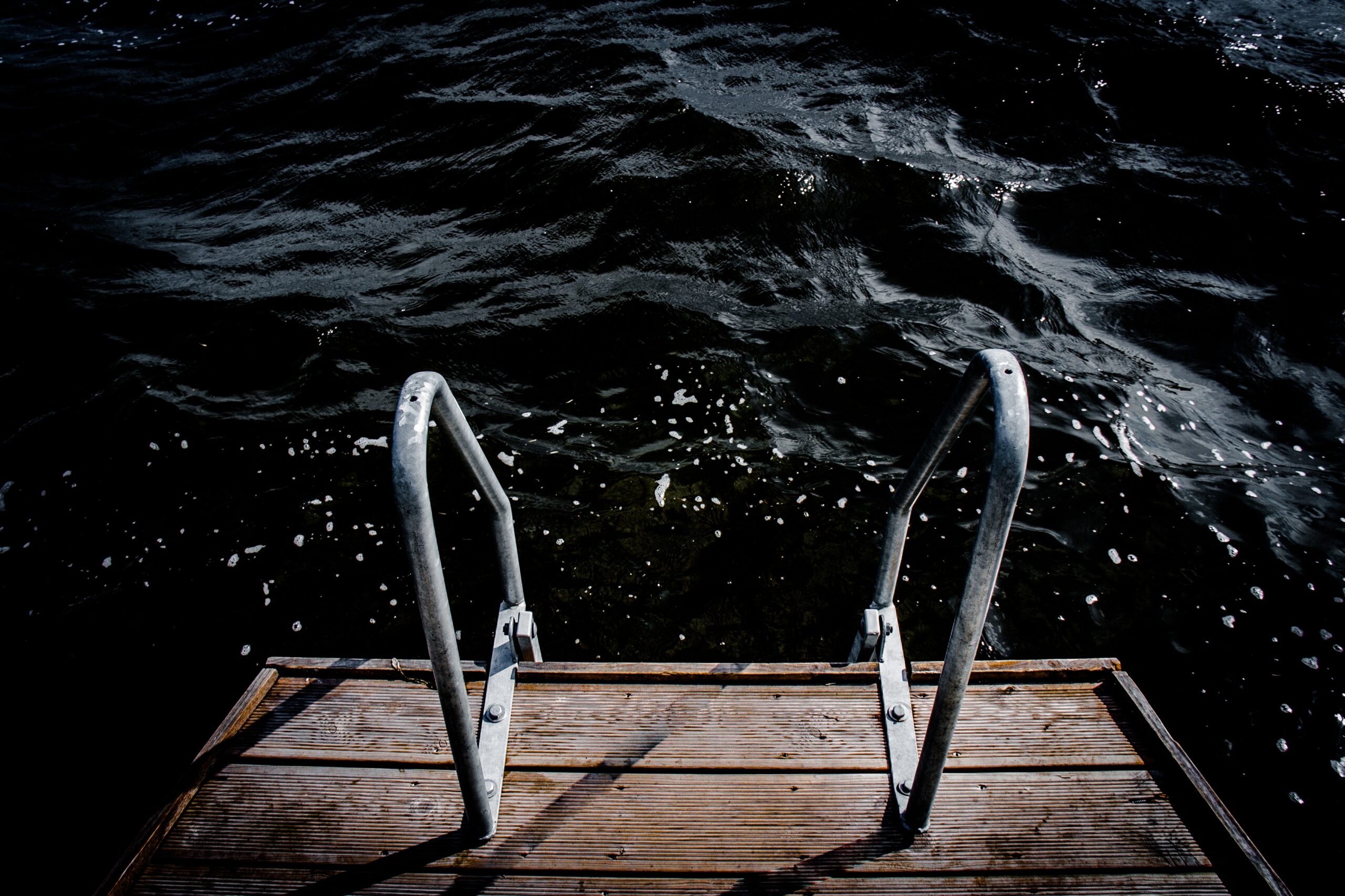 A decking and rails leading down to a dark lake