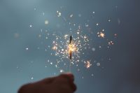 A hand holding up a sparklet against a dark grey sky